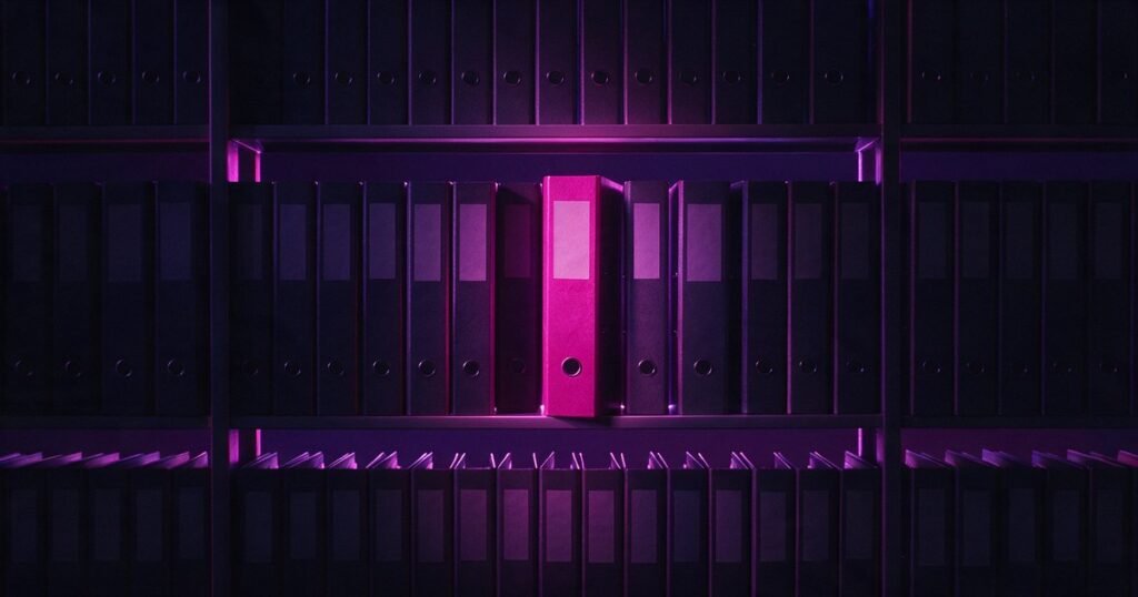 Estante de pastas de arquivo escuras com uma única pasta magenta.
